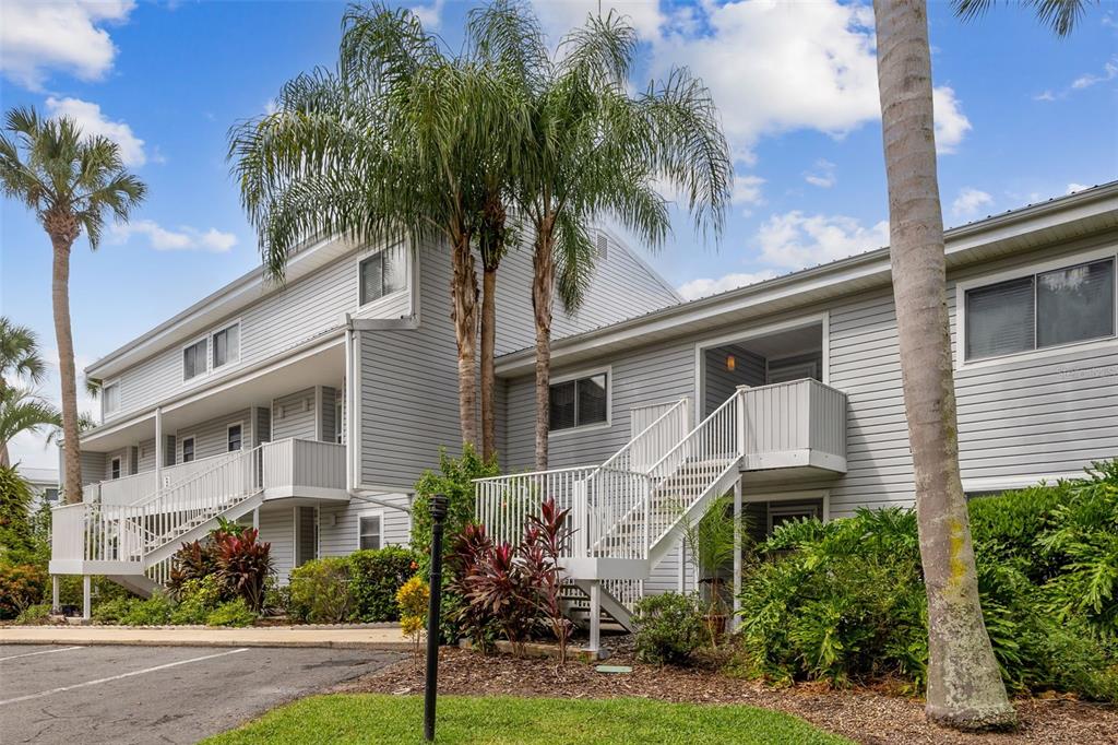 Exterior view of a two-story gray apartment building with white stairs and palm trees — 210 RIVER BEND PLACE UNIT B, WELAKA, FL