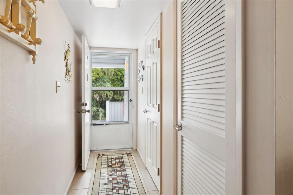 A narrow hallway features a tiled floor, a runner rug, and a glass-paneled exterior door — 210 RIVER BEND PLACE UNIT B, WELAKA, FL