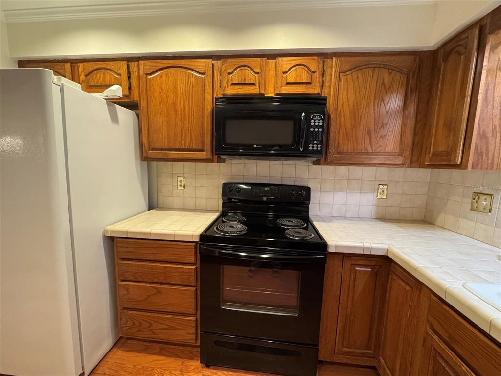 A kitchen island with a black dishwasher and oak cabinets sits on wood flooring — 10 FORT CLINCH HEIGHTS ROAD, FROSTPROOF, FL