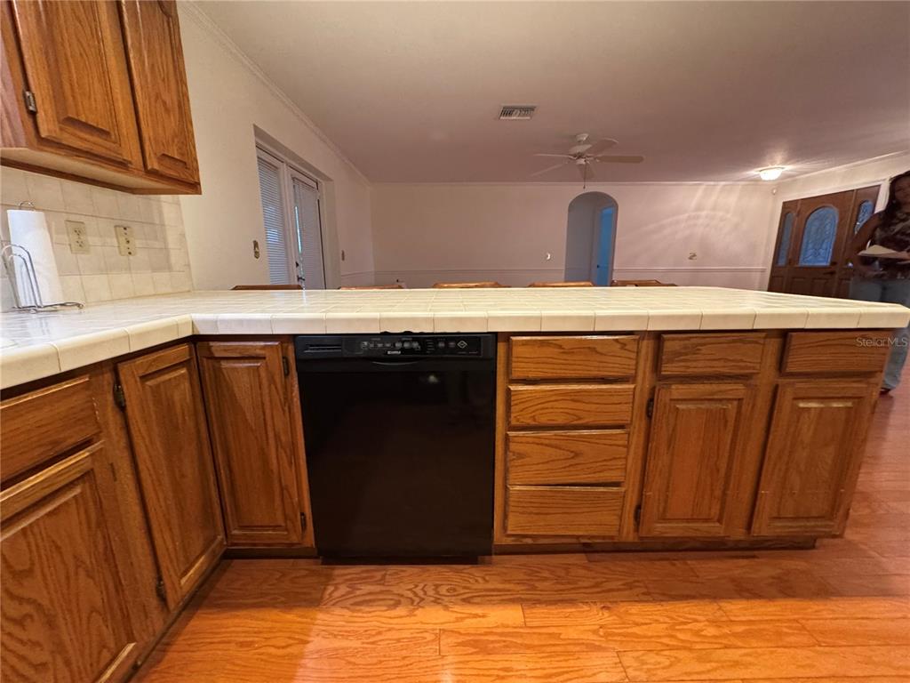 A kitchen features wood cabinets, a tiled island, black appliances, and hardwood flooring — 10 FORT CLINCH HEIGHTS ROAD, FROSTPROOF, FL