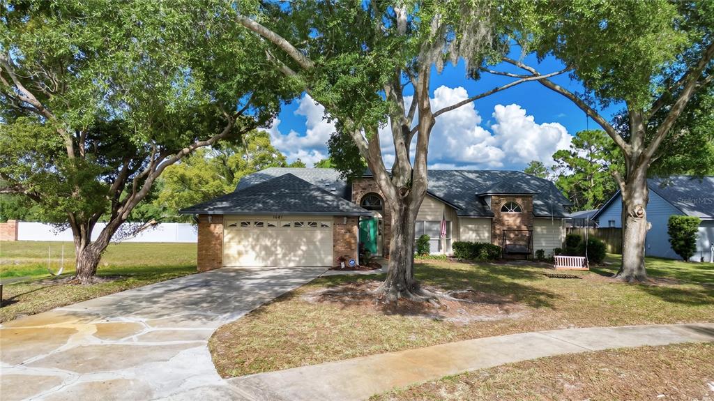 A single-story brick and siding house with a two-car garage and large shade trees — 1681 E SPRING RIDGE CIRCLE, WINTER GARDEN, FL