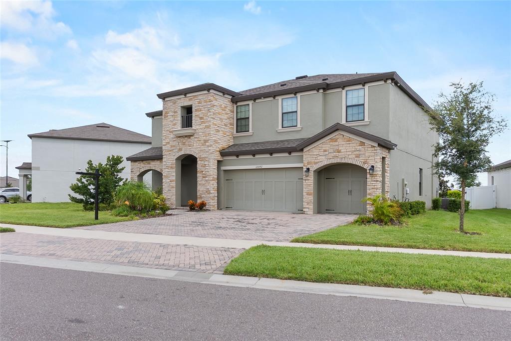 A two-story house with a stone facade, a three-car garage, and a paved driveway — 12642 BERGSTROM BAY DRIVE, RIVERVIEW, FL