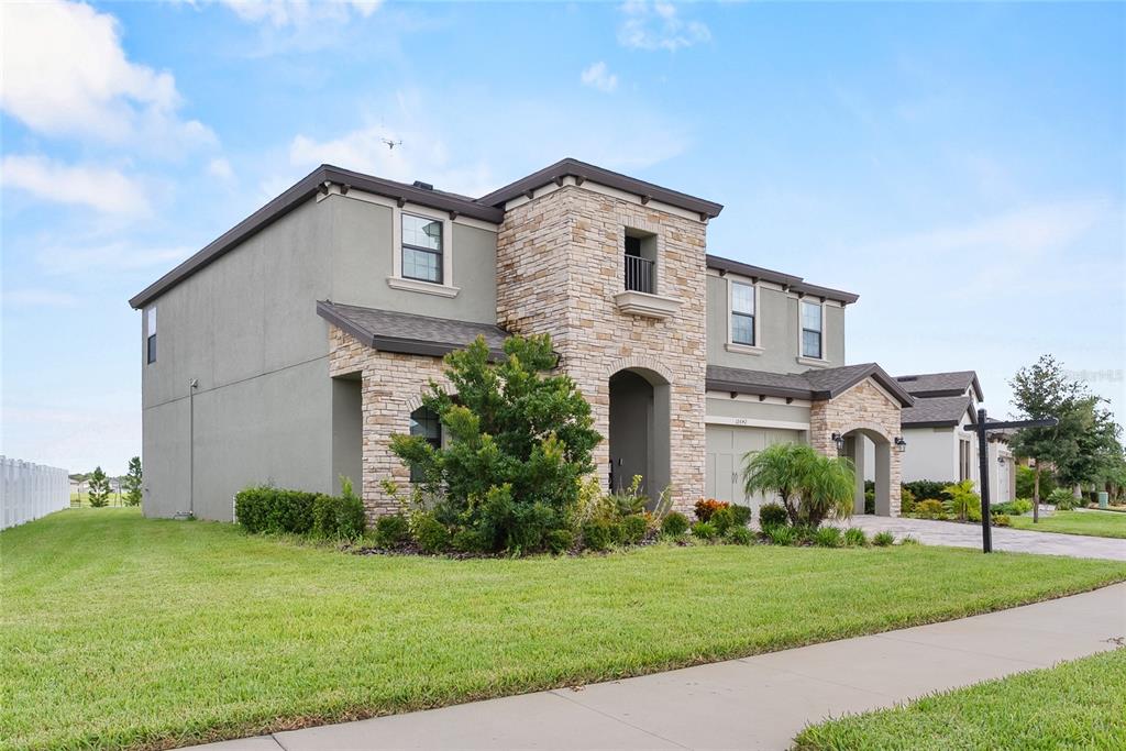 A two-story house with a stone facade, stucco exterior, and a green lawn — 12642 BERGSTROM BAY DRIVE, RIVERVIEW, FL