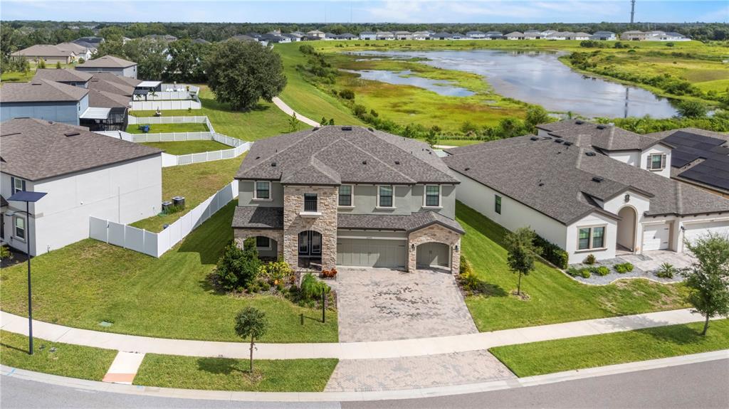 An aerial view shows a two-story suburban house with a stone facade and paved driveway — 12642 BERGSTROM BAY DRIVE, RIVERVIEW, FL