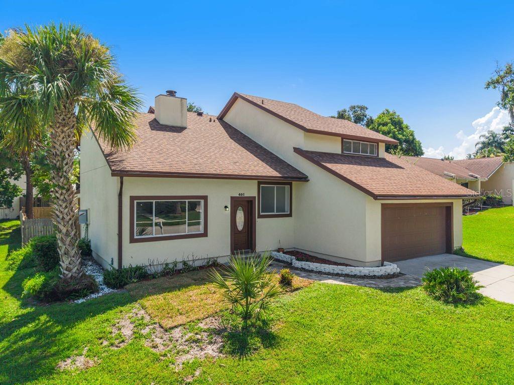 A single-story house with a brown shingled roof, tan stucco exterior, and a front-facing garage — 401 WOODVIEW DRIVE, LONGWOOD, FL