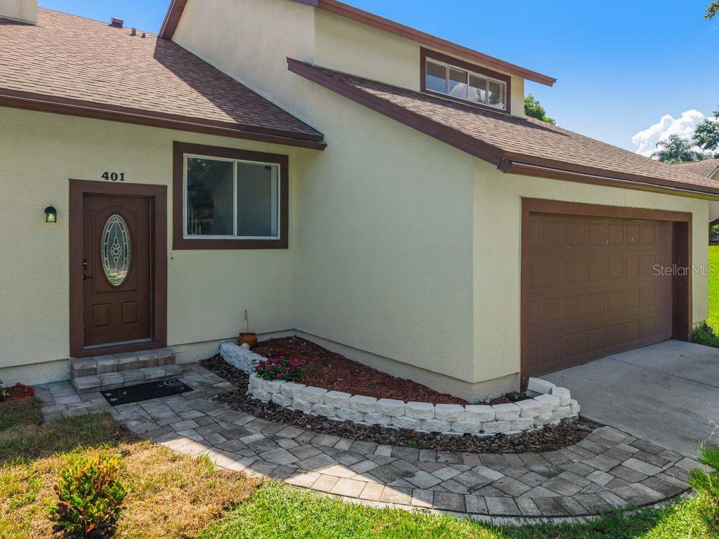 A tan house exterior features a brown front door, a garage, and a stone walkway — 401 WOODVIEW DRIVE, LONGWOOD, FL