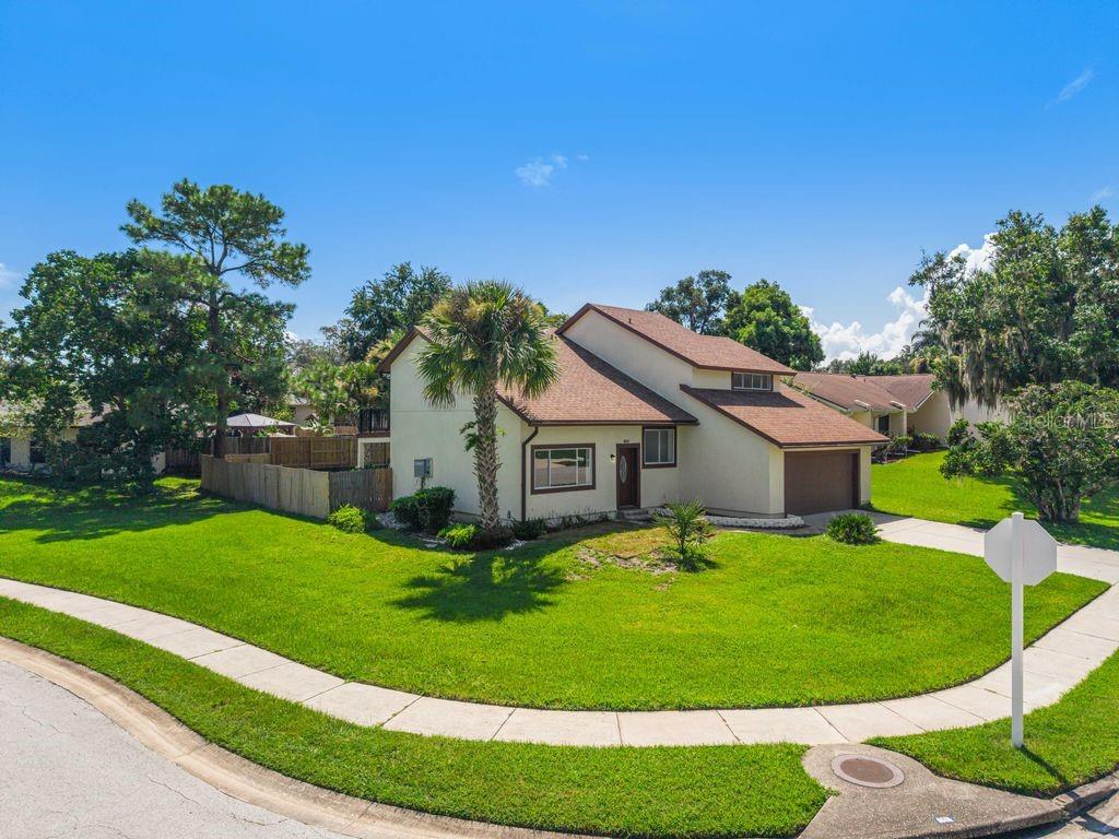 A two-story house with a brown roof and tan siding sits on a corner lot — 401 WOODVIEW DRIVE, LONGWOOD, FL