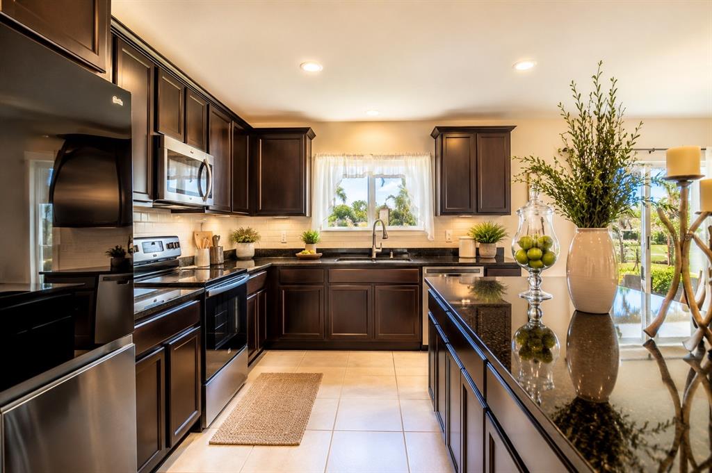 A kitchen with dark wood cabinets, black granite countertops, and stainless steel appliances — 605 SARNER PASS WAY, WINTER HAVEN, FL