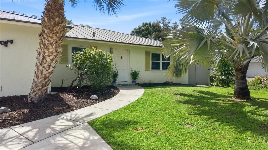 A living room with light tile floors, a sofa, a recliner, and a front door — 6233 ROCKEFELLER AVENUE, SARASOTA, FL