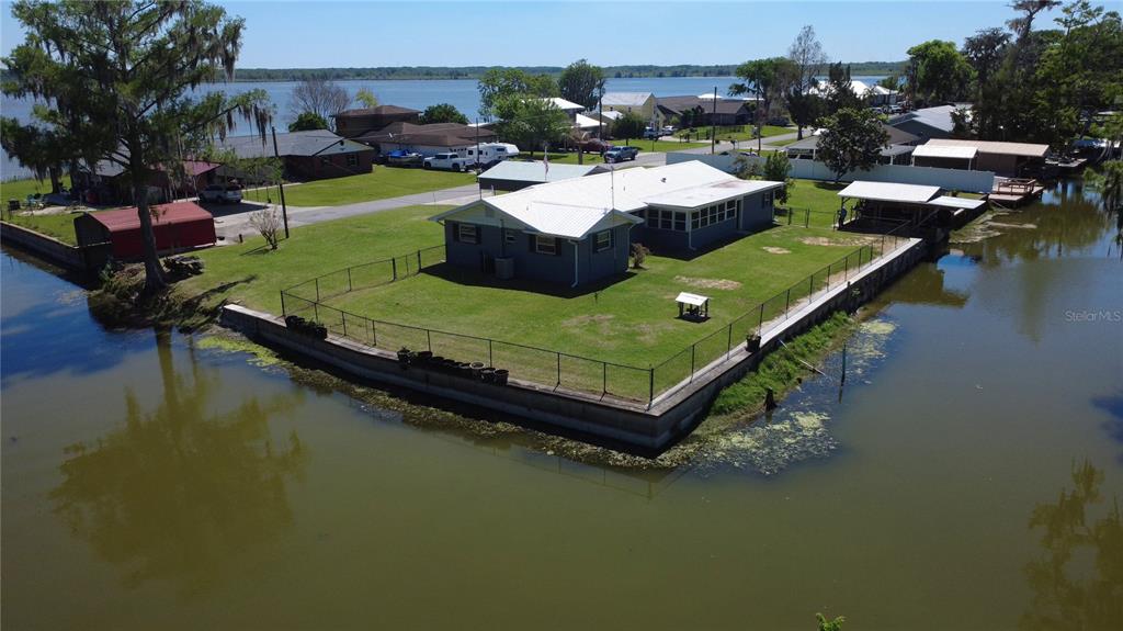 An aerial view shows a house with a white roof situated on a waterfront lot — 664 CR 467, LAKE PANASOFFKEE, FL