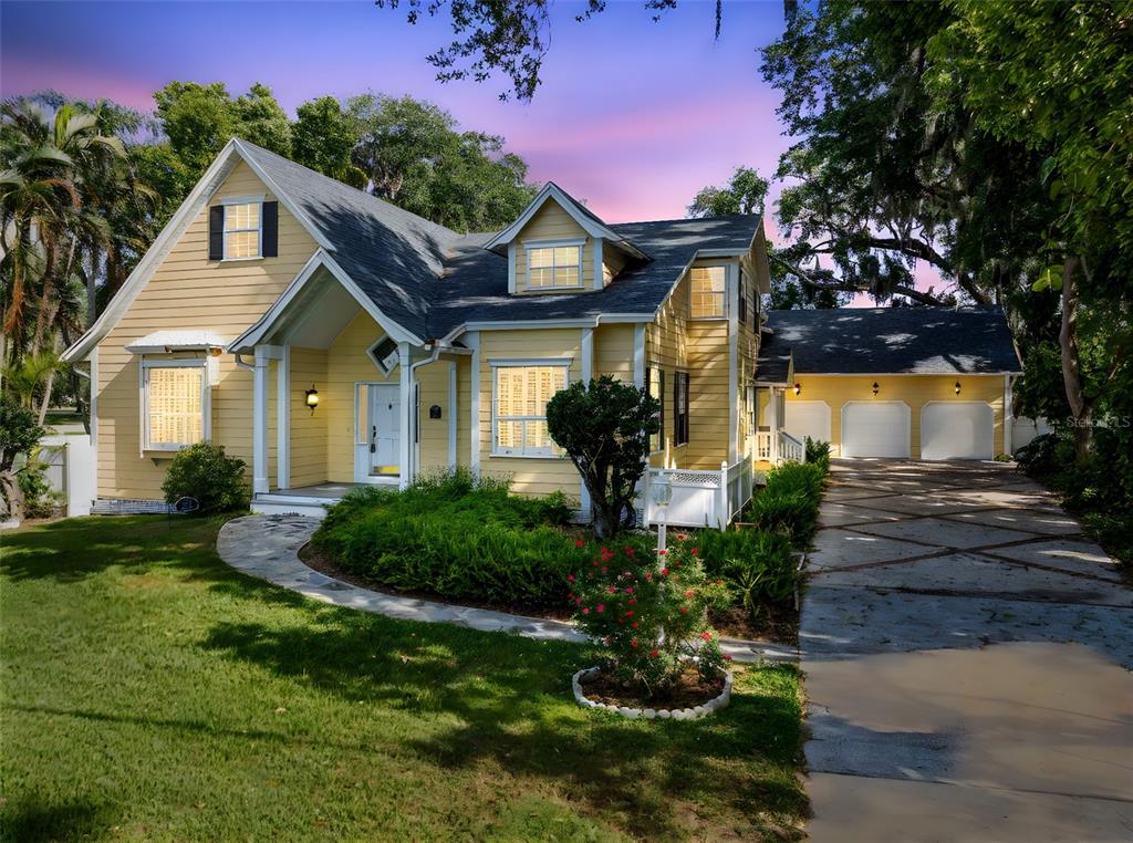 A yellow two-story house with a three-car garage, stone walkway, and landscaped front yard — 910 CYPRESS AVENUE, ST CLOUD, FL