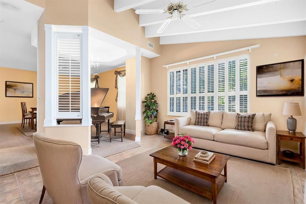 A living room features a beige sofa, a wooden coffee table, and a grand piano nearby — 910 CYPRESS AVENUE, ST CLOUD, FL