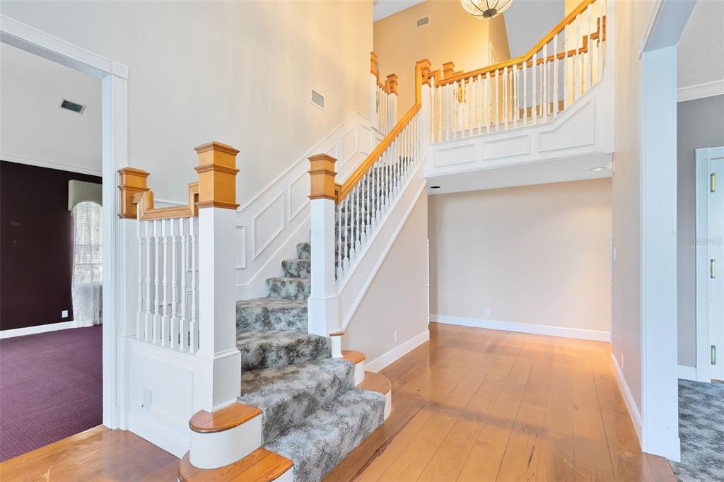 A foyer features hardwood floors, a carpeted staircase with white railings, and a second-floor landing — 910 CYPRESS AVENUE, ST CLOUD, FL