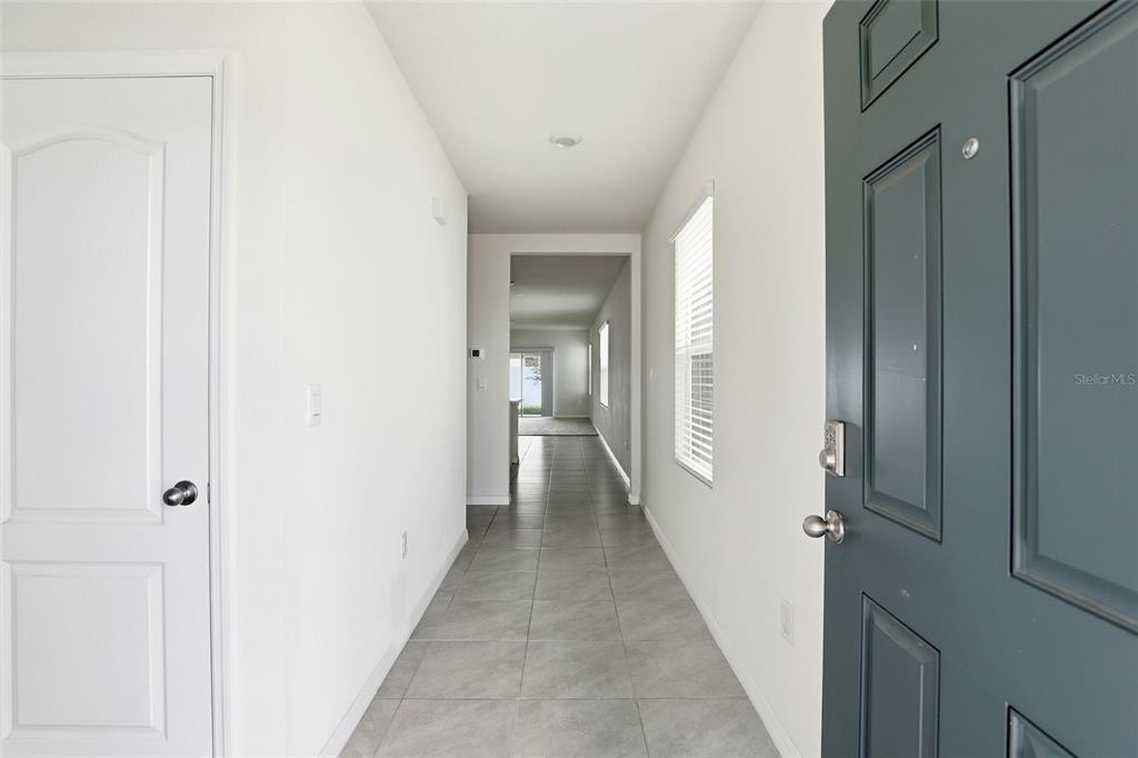 A tiled entryway leads down a hallway toward an open living area with natural light — 6777 HUNTLEIGH HAMMOCK ROAD, HARMONY, FL