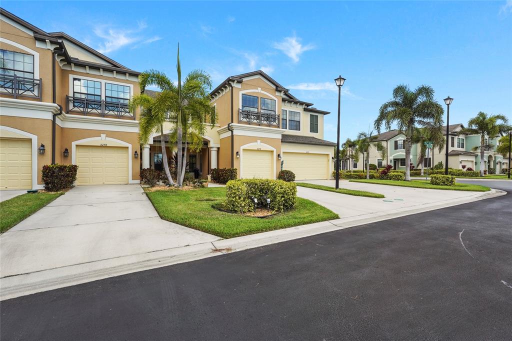 A two-story townhouse exterior features a beige stucco facade, two garage doors, and a walkway — 5274 78TH ST CIRCLE E, BRADENTON, FL