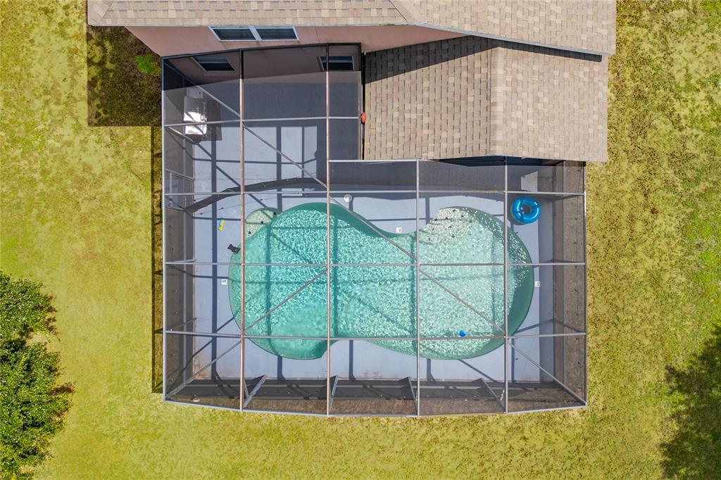 An aerial view shows a swimming pool enclosed by a screen cage behind a house — 1791 ROYAL RIDGE DRIVE, DAVENPORT, FL