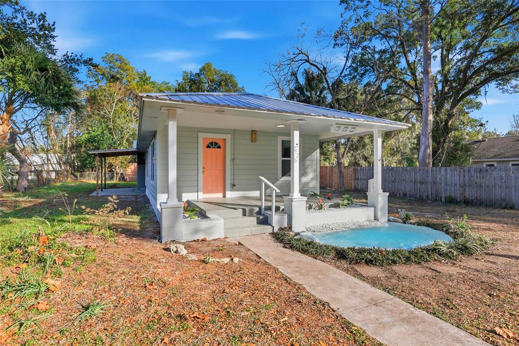 A light green house with a metal roof, orange front door, and a small front pond — 425 SE 2ND STREET, WILLISTON, FL