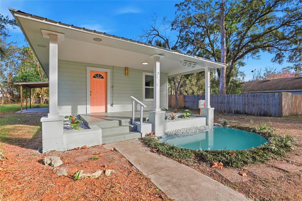 A light green house with a coral door, a front porch, and a small pond — 425 SE 2ND STREET, WILLISTON, FL
