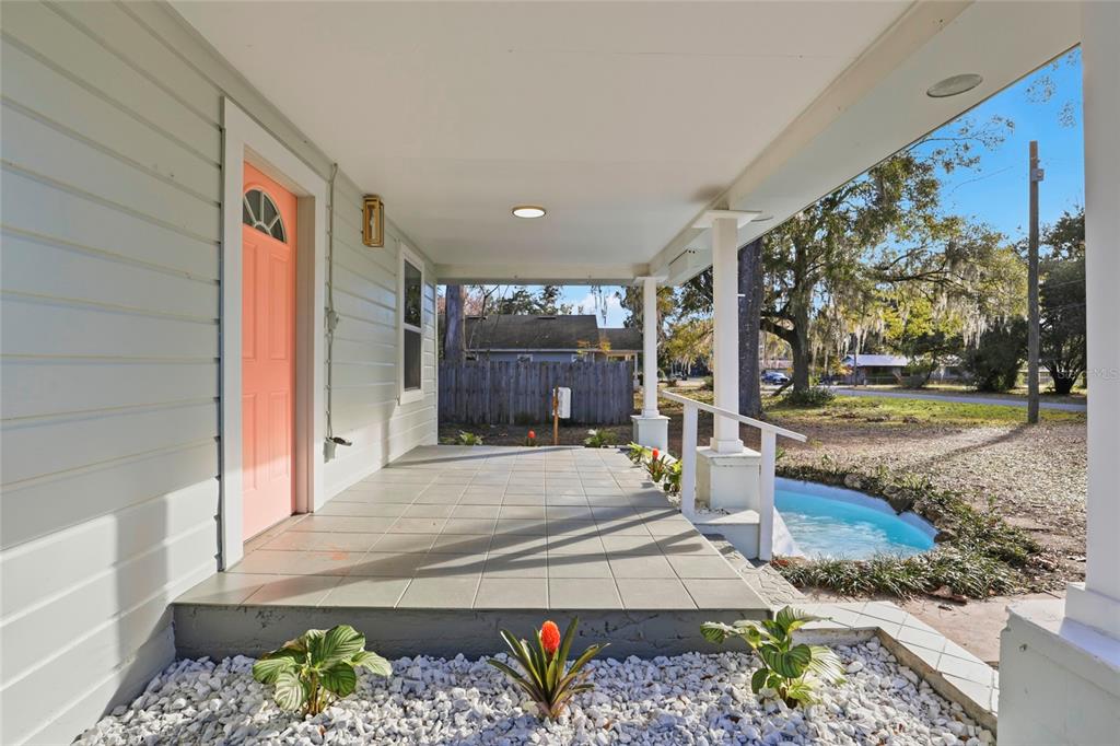 A covered porch features light-colored siding, a coral-colored front door, and a small decorative pond — 425 SE 2ND STREET, WILLISTON, FL