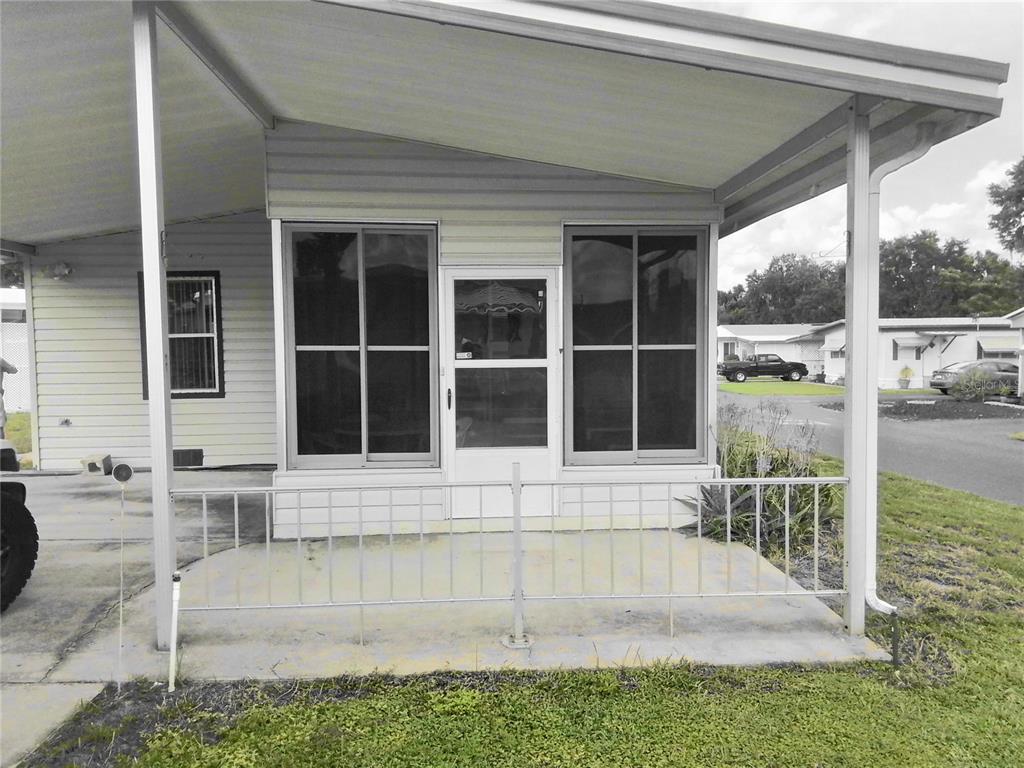 A covered concrete porch with a metal railing sits in front of a mobile home — 915 MARK ROAD, LEESBURG, FL