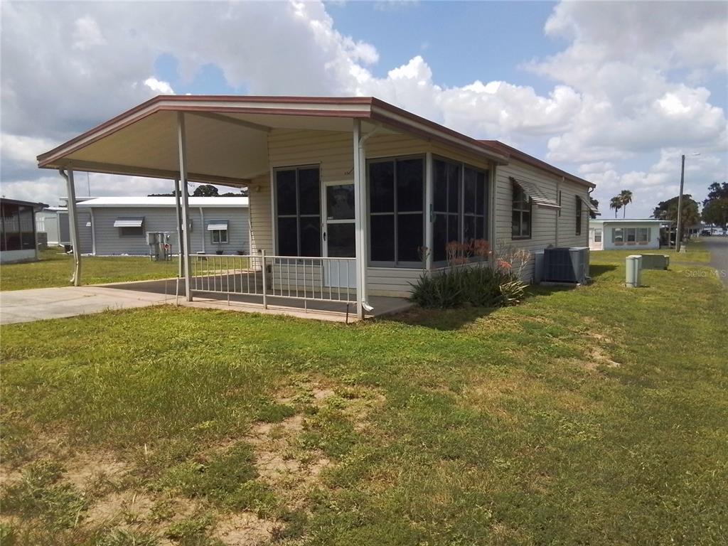 A single-story mobile home features a covered carport, a screened-in porch, and light-colored siding — 915 MARK ROAD, LEESBURG, FL