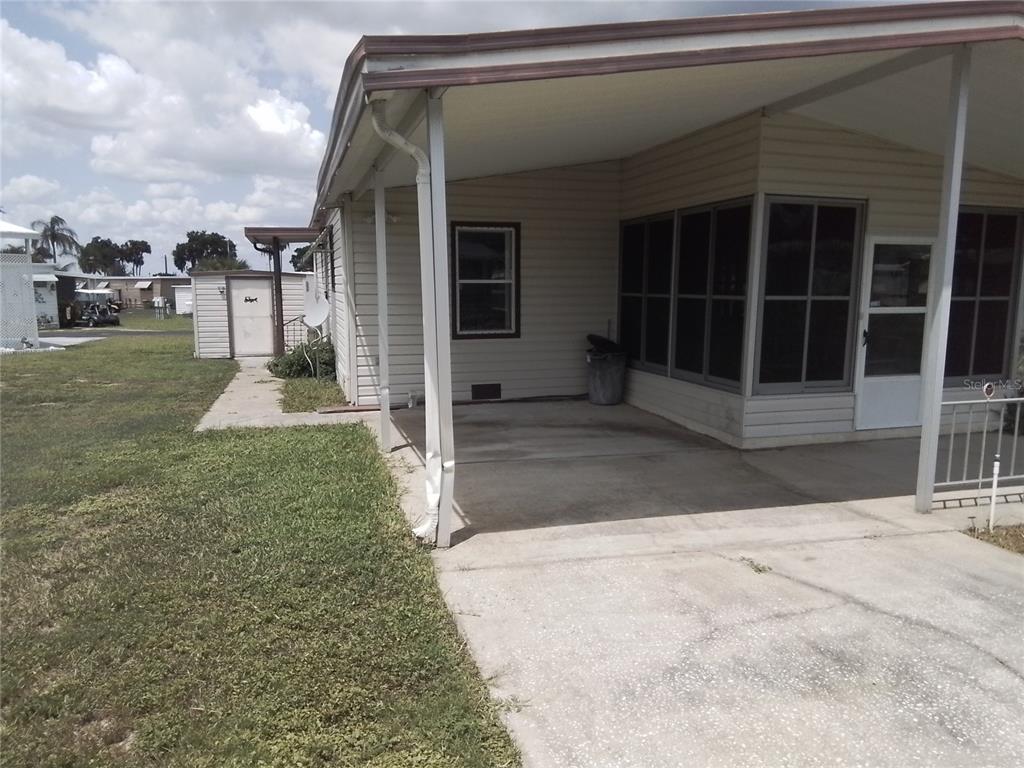 A concrete driveway leads to a covered patio and a mobile home exterior — 915 MARK ROAD, LEESBURG, FL