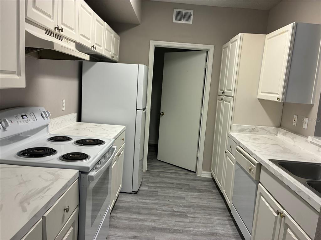 A bathroom vanity with a large mirror, dual sinks, and light-colored cabinetry — 5572 METROWEST BOULEVARD UNIT 209, ORLANDO, FL