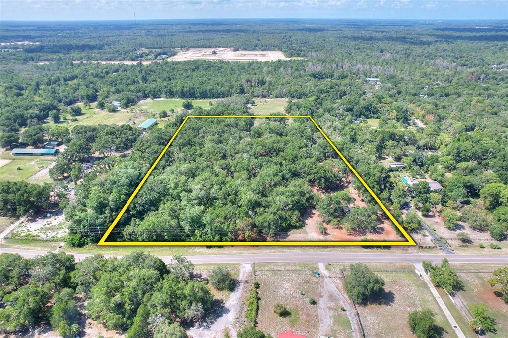An aerial view shows a wooded lot marked by a red arrow — 11000 KITTEN TRAIL, HUDSON, FL