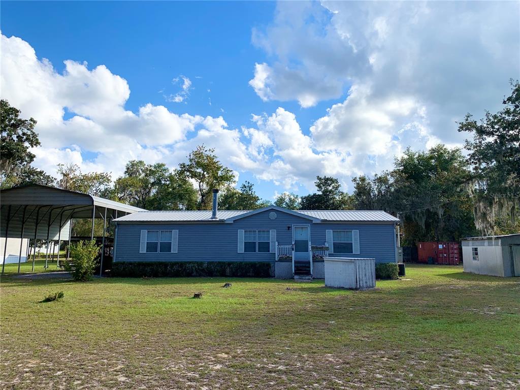 A blue single-wide mobile home with a metal roof and an attached carport — 17630 NE 246TH PLACE, FORT MC COY, FL