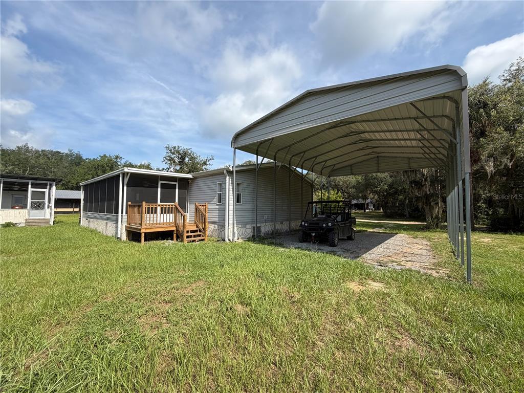 A mobile home with a screened porch, wooden deck, and a large metal carport — 17630 NE 246TH PLACE, FORT MC COY, FL