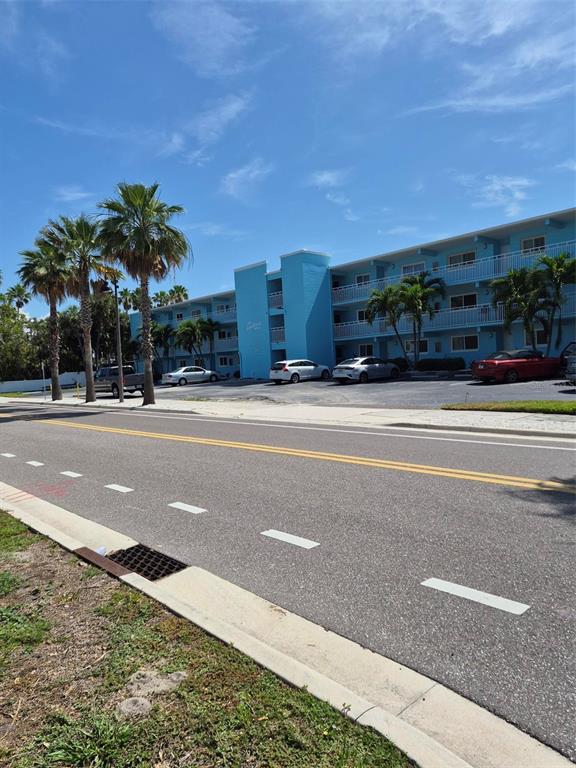 A multi-story blue apartment building stands behind a parking lot and a paved road — 1505 PASS A GRILLE WAY UNIT 31, ST PETE BEACH, FL