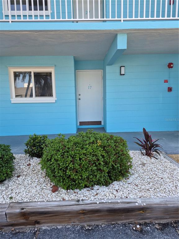 A blue exterior wall features a white door labeled 17, a window, and landscaping — 1505 PASS A GRILLE WAY UNIT 31, ST PETE BEACH, FL