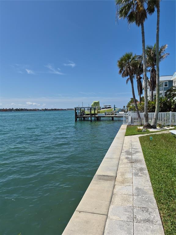 A paved walkway runs alongside a waterfront seawall with a private dock and boat — 1505 PASS A GRILLE WAY UNIT 31, ST PETE BEACH, FL