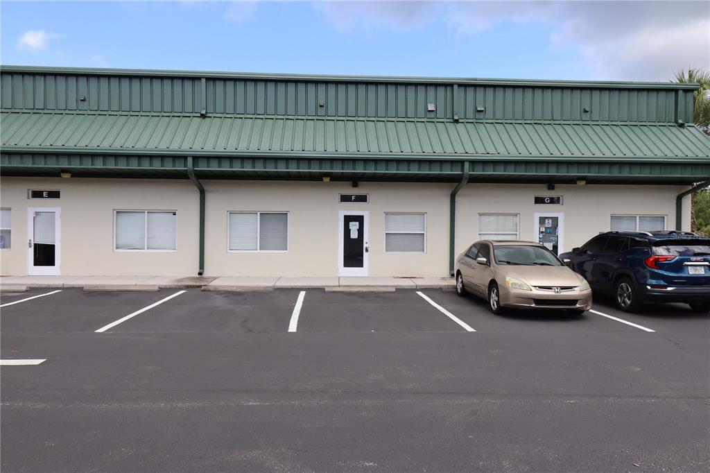 A single-story commercial building with three labeled units and a paved parking lot in front — 144 TRIPLE DIAMOND BOULEVARD UNIT F, NOKOMIS, FL