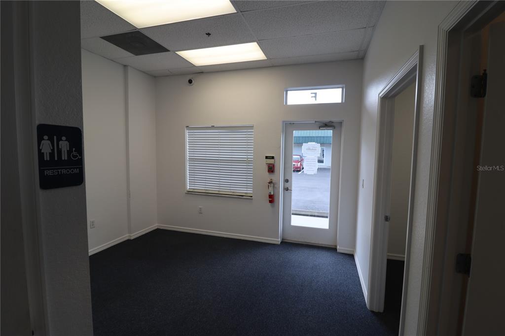 An office space features dark carpet, white walls, a restroom sign, and a glass-paneled door — 144 TRIPLE DIAMOND BOULEVARD UNIT F, NOKOMIS, FL