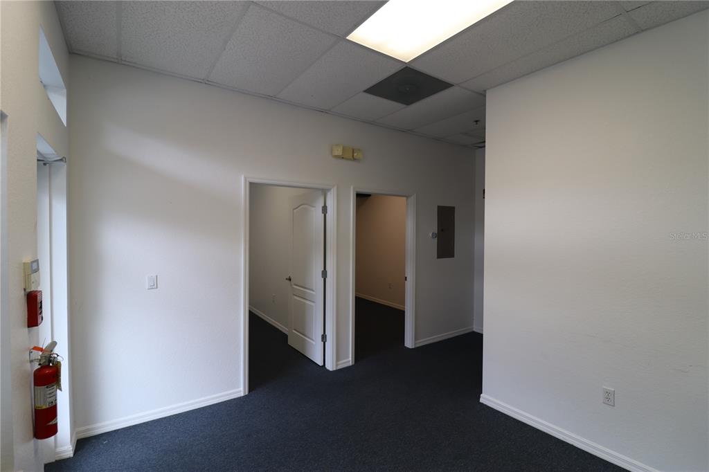 An office interior features white walls, dark carpeting, a drop ceiling, and two open doorways — 144 TRIPLE DIAMOND BOULEVARD UNIT F, NOKOMIS, FL