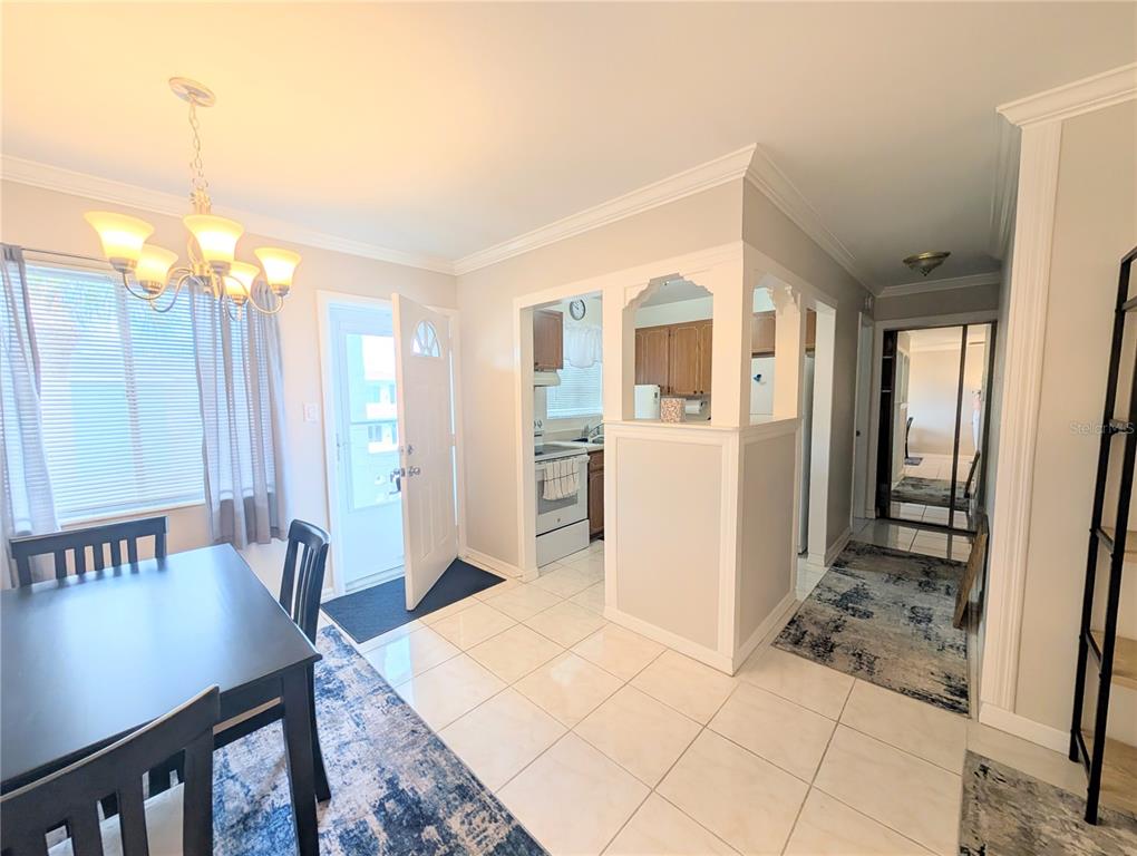 A dining area with a tile floor leads to a kitchen and a hallway with mirrors — 1839 SUNNY DRIVE UNIT E36, BRADENTON, FL