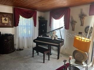 A room with a grand piano, wood-paneled ceiling, red valance curtains, and a table lamp — 423 SW ALDERENE PARK WAY, MADISON, FL