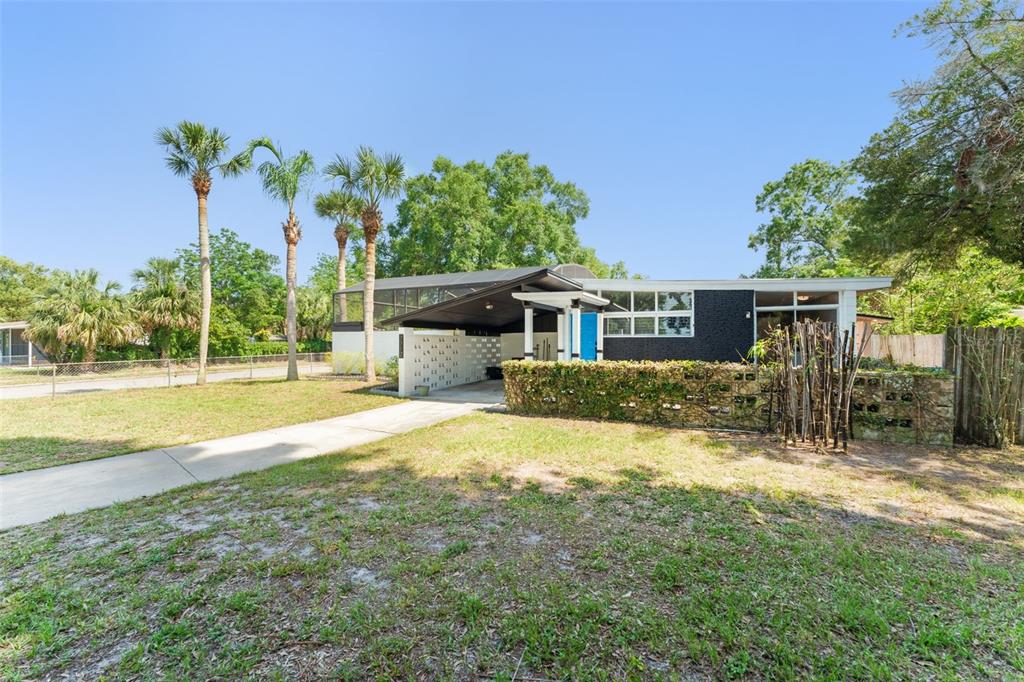 A mid-century modern house with a carport, breeze block wall, and palm trees in front — 7712 HOOSIER PLACE, ORLANDO, FL