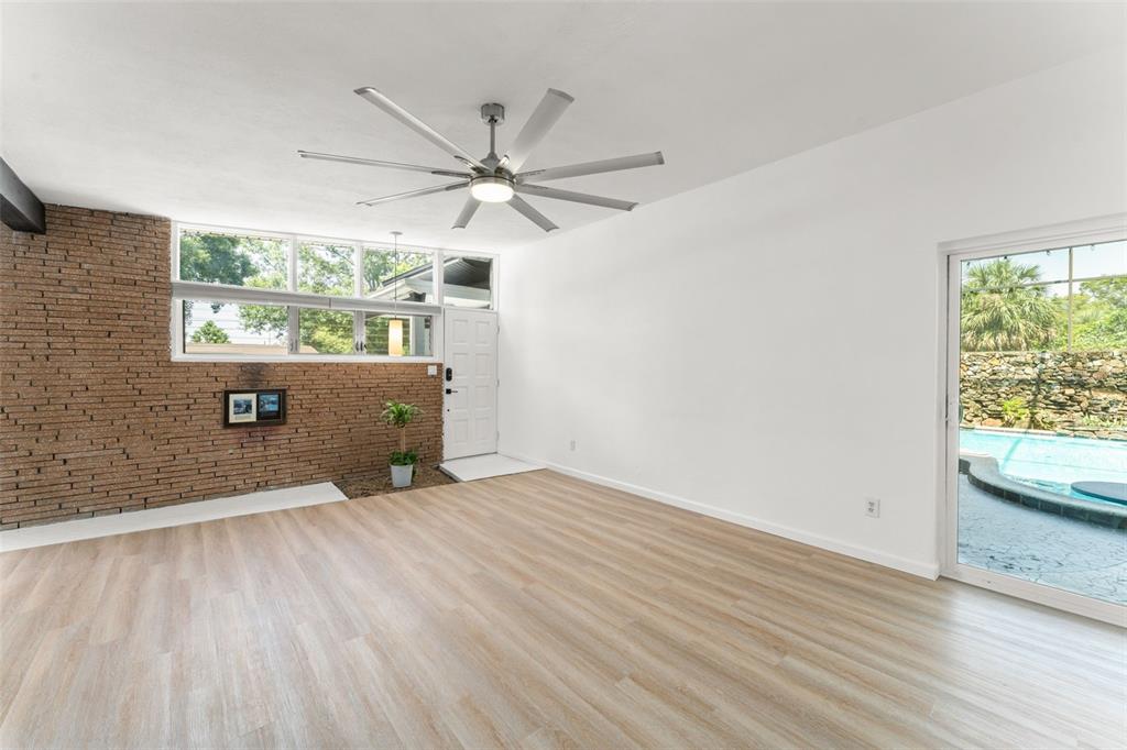 A living room features light wood flooring, a brick accent wall, and a sliding glass door — 7712 HOOSIER PLACE, ORLANDO, FL