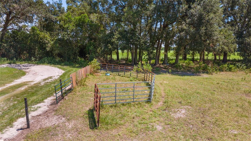 An aerial view shows a metal livestock pen situated in a grassy field near trees — NW 65TH AVENUE, TRENTON, FL