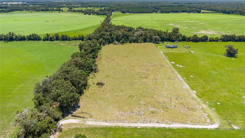 An aerial view shows a large, rectangular grassy lot bordered by trees and farmland — NW 65TH AVENUE, TRENTON, FL
