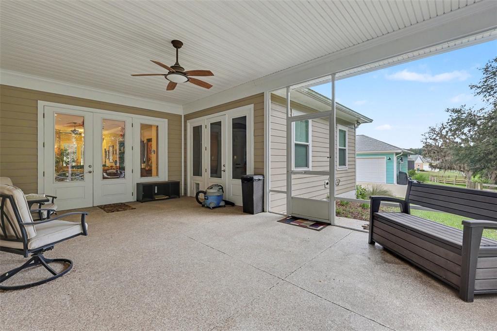 A covered screened-in patio features a concrete floor, a ceiling fan, and outdoor furniture — 1182 FIESTA KEY CIRCLE, LADY LAKE, FL