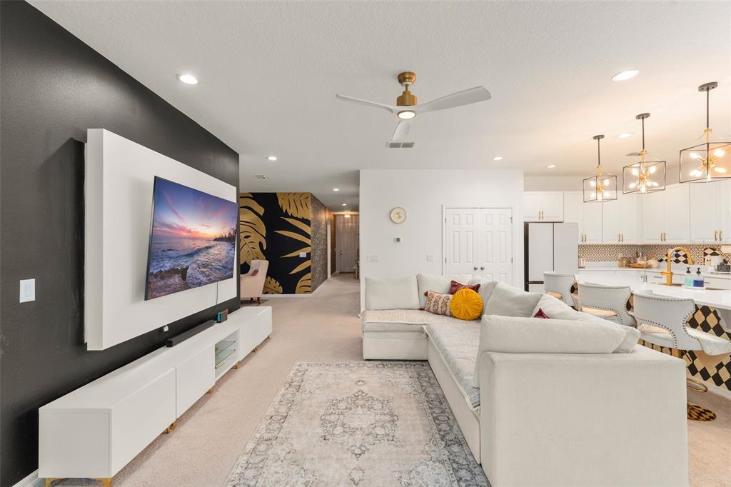 A hallway features dark patterned wallpaper, a console table with a mirror, and carpeted flooring — 1195 CRANE TALON WAY, SANFORD, FL