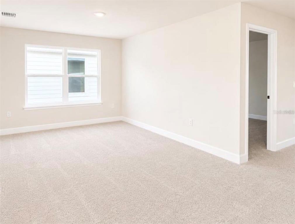An empty bedroom features beige carpet, light-colored walls, a single window, and white trim — 7727 BENT TREE LOOP, ST CLOUD, FL