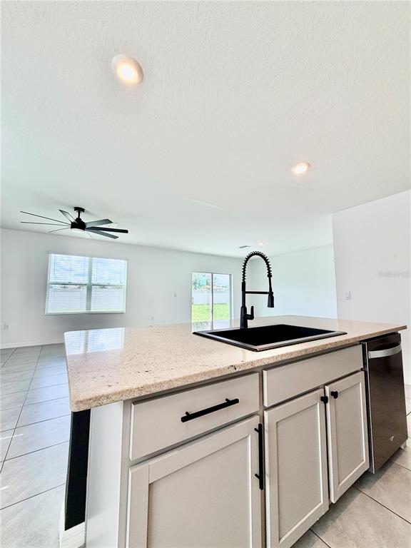A kitchen island with a black sink and faucet sits in an open-concept living space — 34110 JASPER STONE DRIVE, WESLEY CHAPEL, FL
