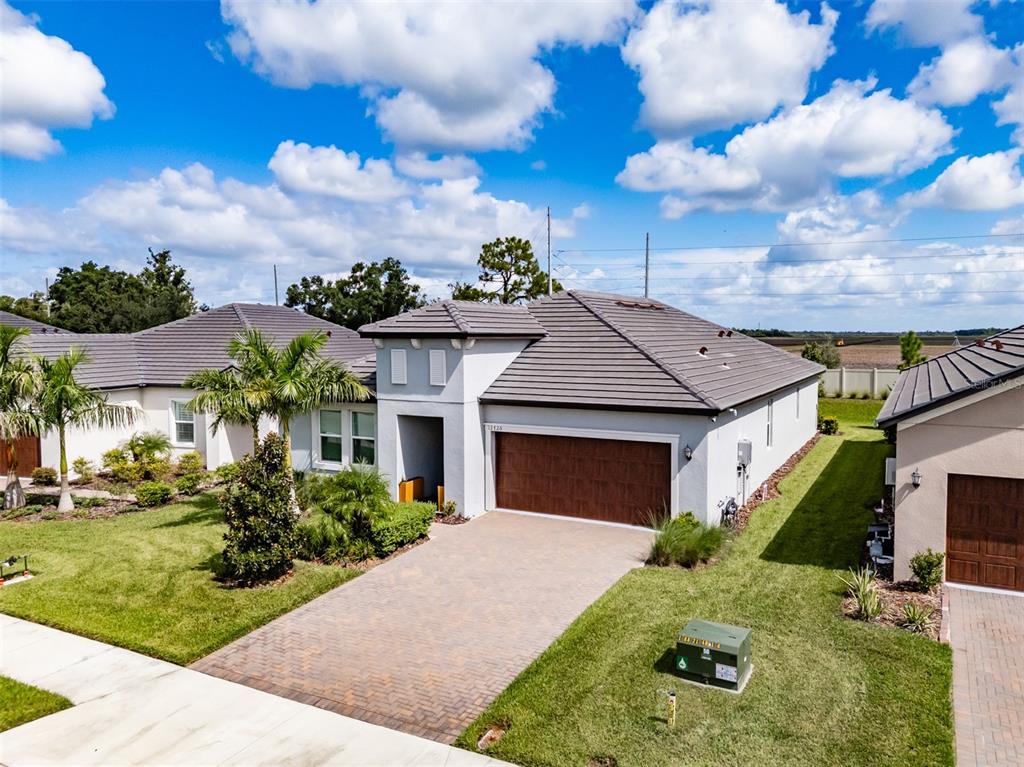 An exterior view of a single-story suburban house with a paved driveway and tiled roof — 12720 TAHITIAN PEARL, PARRISH, FL