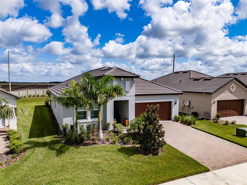 A single-story suburban house with a tiled roof, palm trees, and a paved driveway — 12720 TAHITIAN PEARL, PARRISH, FL