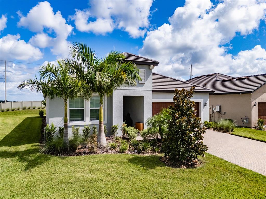 A single-story house with a tiled roof, palm trees, and a paved driveway — 12720 TAHITIAN PEARL, PARRISH, FL