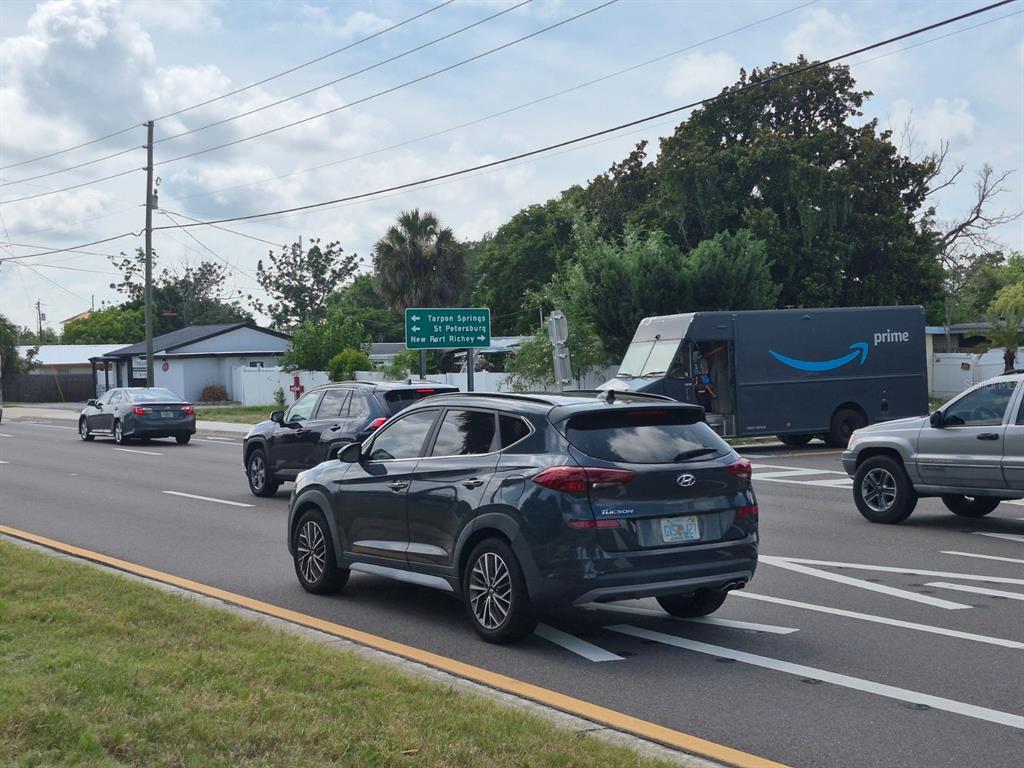 A street-level view shows a crosswalk, a road sign, and a small building with a car — 4007 FLAMINGO DRIVE, NEW PORT RICHEY, FL